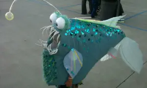 Un bambino indossa un costume da pesce lanterna fai da te, perfetto per un tema mare. Le paillettes blu e la canna da pesca con la luce lo rendono unico.