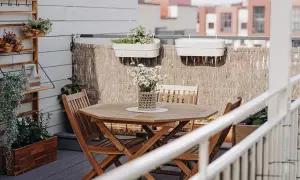 Un tavolo e sedie in legno per arredare balcone piccolo. Piante in vaso e decorazioni creano un angolo accogliente.