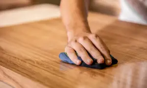 Mano che lucida un mobile in legno. Scopri come togliere graffi dai mobili laccati con cura e pazienza.