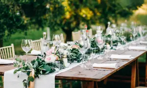 Tavola apparecchiata all'aperto con fiori, candele e bicchieri. Un'idea per le decorazioni matrimonio fai da te.