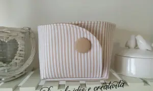 Portaoggetti in stoffa da appendere fai da te, a righe beige e bianche, con bottone decorativo. Perfetto per organizzare piccoli oggetti.