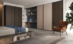 Un accogliente angolo lettura camera da letto con poltrona in pelle, scrivania e libreria a muro.