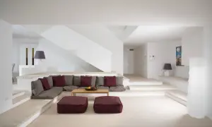 Un accogliente salotto in muratura con divano angolare, cuscini colorati e un tavolino di legno.