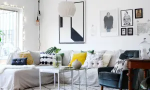 Un accogliente soggiorno fai da te con divano bianco, cuscini colorati e stampe artistiche alle pareti.
