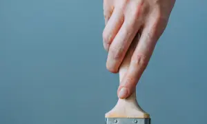 Mano che tiene un pennello, utile per capire come togliere lo smalto dai vestiti.