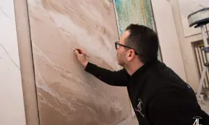 Artista crea effetti materici su pannello, mostrando diversi tipi di pittura per interni.