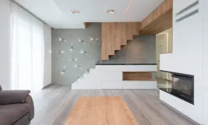 Soggiorno moderno con diversi tipi di scale: una a sbalzo in legno, una a vista bianca e una integrata in mobili contenitori.