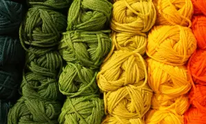 Gomitoli di lana colorata, con un'abbondanza di macchie gialle che si fondono con il verde e l'arancione, pronti per un progetto creativo.