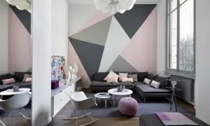 Soggiorno moderno con parete decorata con motivi geometrici in pittura rosa, grigio e bianco. Idee decorazioni pareti pittura per un look audace.