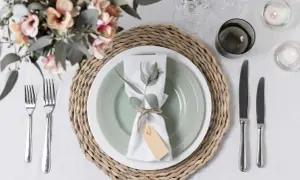 Tovagliolo decorato con rametto e cartellino, un'idea per portatovaglioli fai da te. Tavola apparecchiata con fiori, candele e posate.