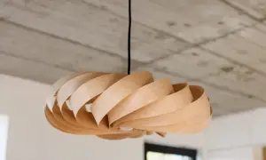 Lampadario in legno fai da te, con lamelle curve che creano un effetto a spirale. Luce soffusa e design naturale.