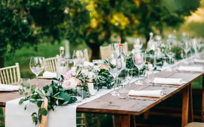 Tavola apparecchiata all'aperto con fiori, candele e bicchieri. Un'idea per le decorazioni matrimonio fai da te.