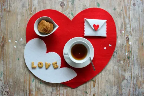 Tovagliette colazione fai da te a forma di cuore, con biscotti, tè e una busta con un cuore.