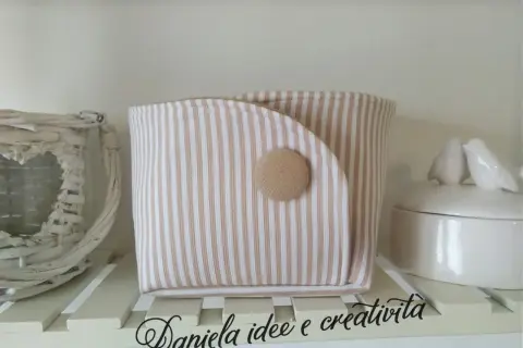 Portaoggetti in stoffa da appendere fai da te, a righe beige e bianche, con bottone decorativo. Perfetto per organizzare piccoli oggetti.