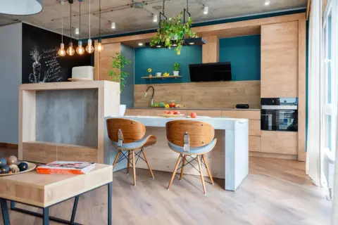Cucina moderna con isola centrale e sedie in legno. L'arredamento mix and match crea un ambiente accogliente, con dettagli industriali e tocchi di colore vivace.