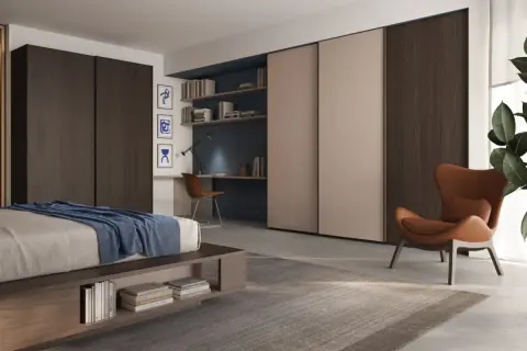 Un accogliente angolo lettura camera da letto con poltrona in pelle, scrivania e libreria a muro.