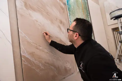 Artista crea effetti materici su pannello, mostrando diversi tipi di pittura per interni.