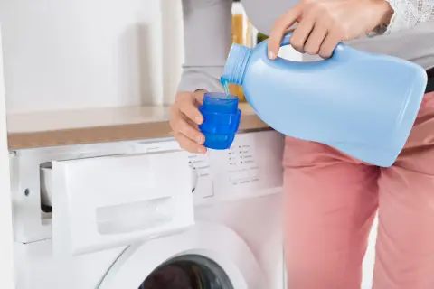 Versando ammorbidente nella lavatrice, sperando che non macchi i vestiti.