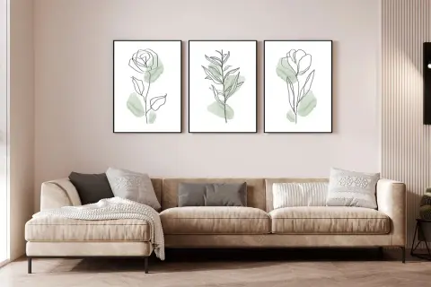 Divano beige in un soggiorno al piano terra poco luminoso, con tre quadri botanici minimalisti e una lampada da parete.