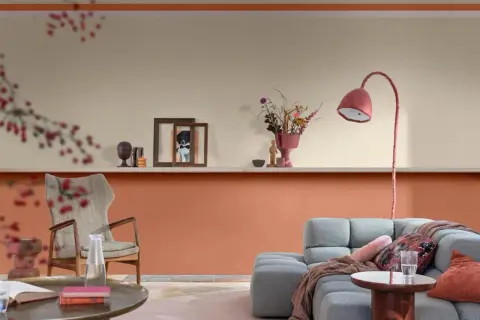 Soggiorno con pareti bicolore: la parte inferiore è color terracotta, quella superiore color crema. Arredamento moderno con divano grigio e poltrona.