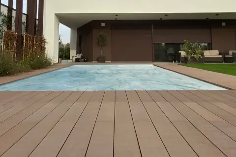 Pavimento per balcone in legno composito, con piscina coperta e zona relax sullo sfondo.