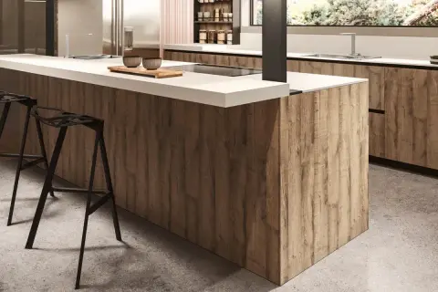 Modern kitchen island with wood-look melamine cabinets and white countertop, featuring black bar stools.