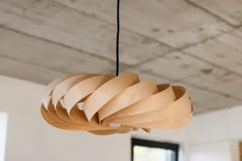 Lampadario in legno fai da te, con lamelle curve che creano un effetto a spirale. Luce soffusa e design naturale.