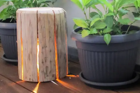 Lampada tronco legno fai da te illumina con calore il deck, creando un'atmosfera accogliente tra le piante in vaso.