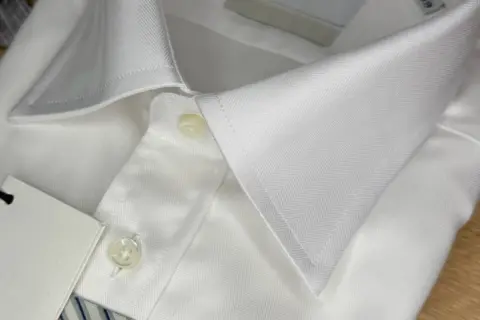 Dettaglio di una camicia bianca con colletto e bottoni. Un'idea su come sbiancare una camicia bianca ingiallita.