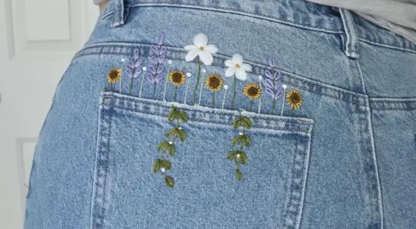 Top di jeans fai da te con ricamo floreale: lavanda, girasoli e margherite adornano la tasca posteriore, creando un look unico e primaverile.