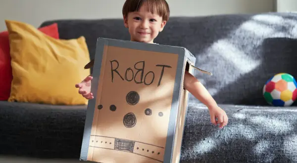 Bambino sorridente con travestimenti cartoni animati fai da te da robot, creato con una scatola di cartone.