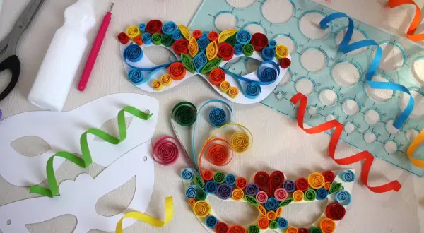 Maschere di carnevale da realizzare con i bambini: forbici, colla, stencil e strisce colorate per creare capolavori di quilling.