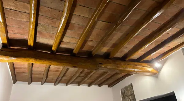 Travi in legno con tetto in cotto, protette da un efficace trattamento antitarlo per preservare la bellezza storica.