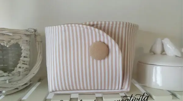 Portaoggetti in stoffa da appendere fai da te, a righe beige e bianche, con bottone decorativo. Perfetto per organizzare piccoli oggetti.