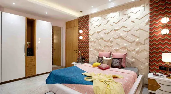 Camera da letto moderna con letto, armadi bianchi e un lampadario a sfere. La parete dietro il letto ha un pannello 3D e una carta da parati a zig-zag.