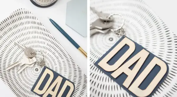 Portachiavi fai da te per la festa del papà con scritta "DAD" in legno su fondo blu. Un'idea regalo originale e personalizzata.