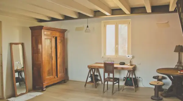 Arredare casa in campagna fai da te: armadio antico, specchio, scrivania rustica e tavolino con sgabelli.