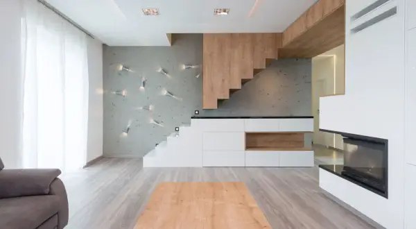 Soggiorno moderno con diversi tipi di scale: una a sbalzo in legno, una a vista bianca e una integrata in mobili contenitori.