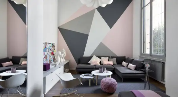 Soggiorno moderno con parete decorata con motivi geometrici in pittura rosa, grigio e bianco. Idee decorazioni pareti pittura per un look audace.