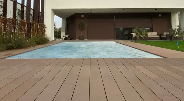 Pavimento per balcone in legno composito, con piscina coperta e zona relax sullo sfondo.