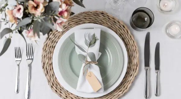 Tovagliolo decorato con rametto e cartellino, un'idea per portatovaglioli fai da te. Tavola apparecchiata con fiori, candele e posate.
