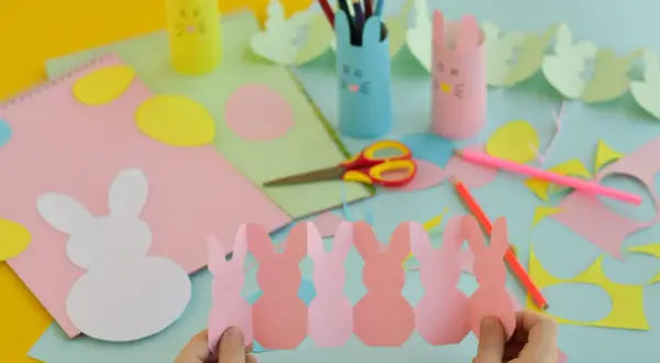 Bambini creano lavoretti di Pasqua scuola primaria: coniglietti di carta, uova colorate e porta-matite a tema.
