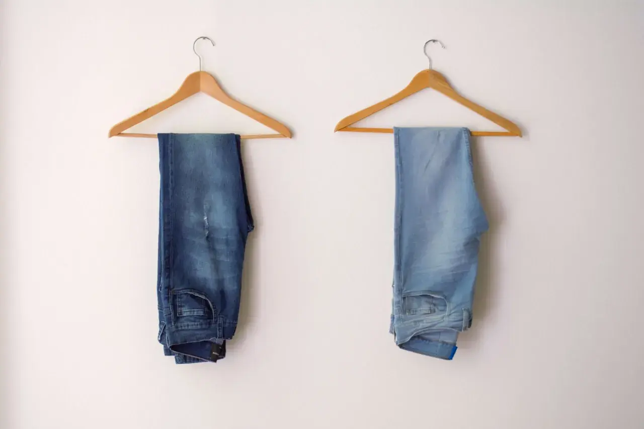 Due paia di jeans appesi: uno scuro, l'altro chiaro. Scopri come scolorire i jeans senza candeggina per ottenere questo effetto.
