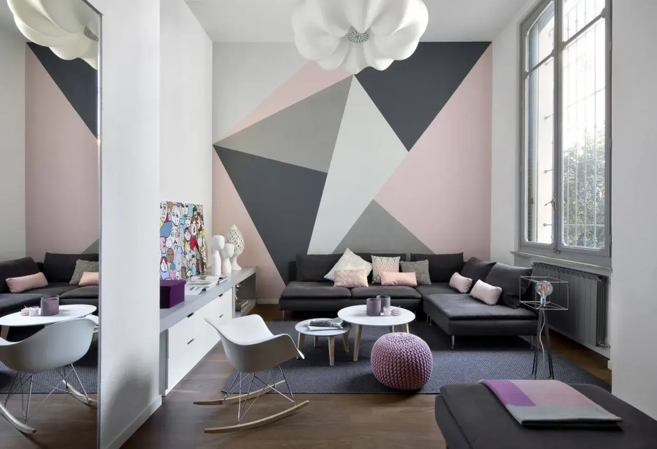 Soggiorno moderno con parete decorata con motivi geometrici in pittura rosa, grigio e bianco. Idee decorazioni pareti pittura per un look audace.