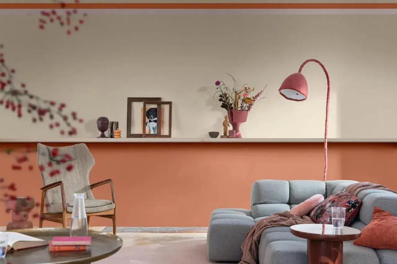 Soggiorno con pareti bicolore: la parte inferiore è color terracotta, quella superiore color crema. Arredamento moderno con divano grigio e poltrona.
