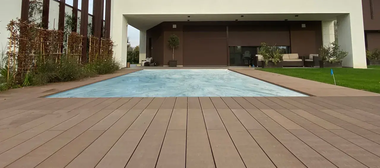 Pavimento per balcone in legno composito, con piscina coperta e zona relax sullo sfondo.