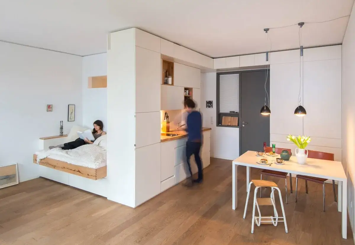 Soggiorno con letto a scomparsa, cucina a vista e zona pranzo. Ottime idee arredo casa piccola per sfruttare ogni spazio.