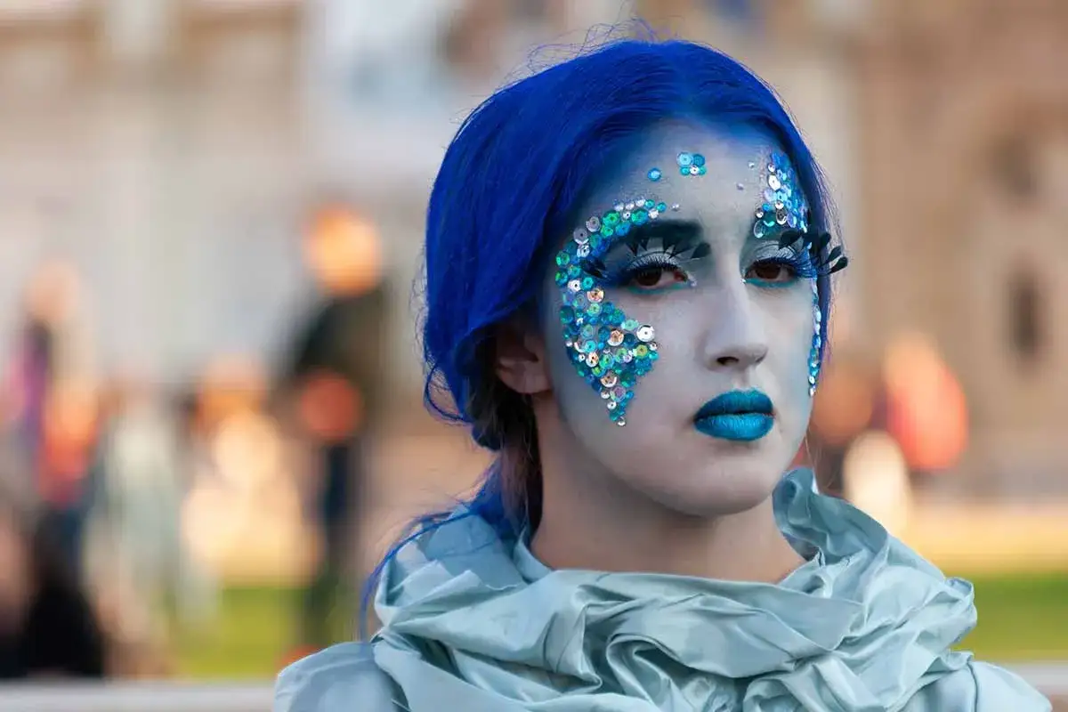 Ragazza con trucco da sirena, capelli blu e paillettes scintillanti. Un esempio di costumi carnevale tema mare fai da te.