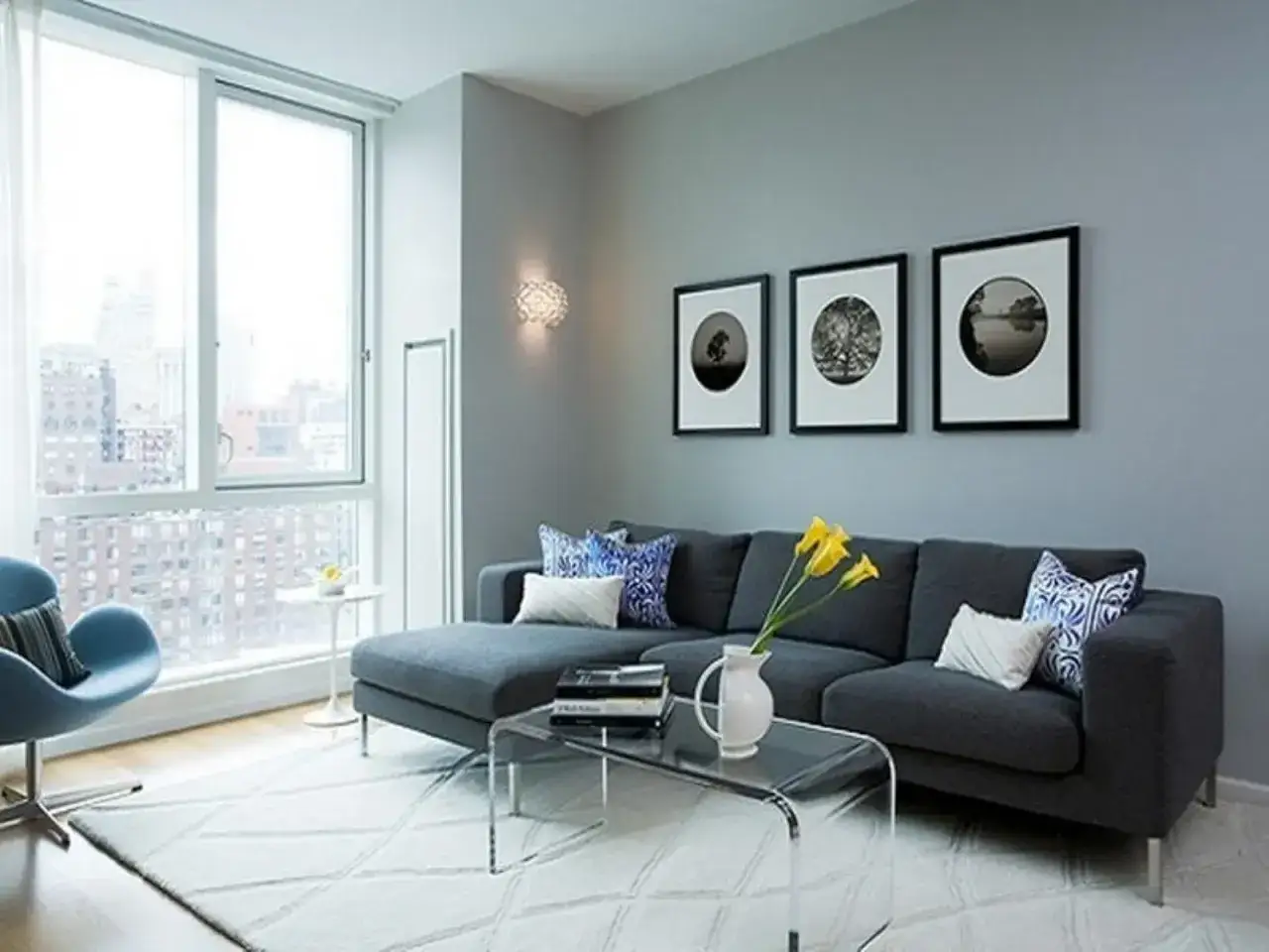 Soggiorno moderno con divano grigio, quadri astratti e lampada di design. Ottime idee decorazioni pareti pittura per un tocco di stile.