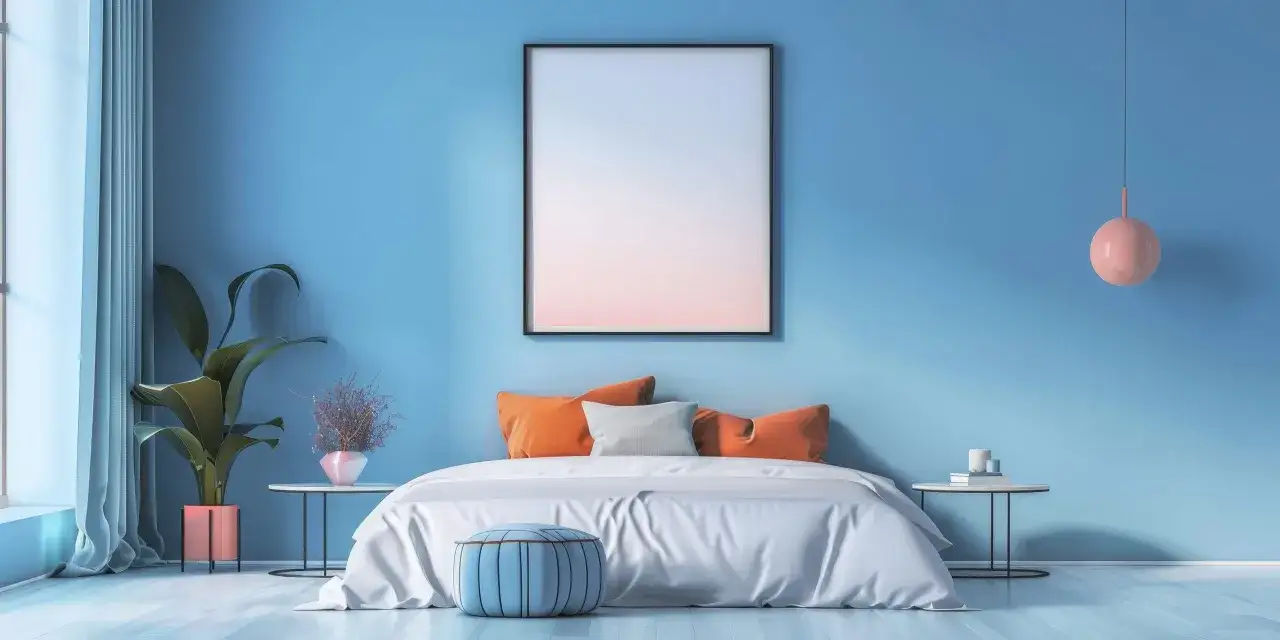 Camera da letto con pareti azzurre, letto bianco con cuscini arancioni e grigi, pouf blu. Un quadro astratto e una pianta completano l'arredo, creando un'atmosfera rilassante in linea con i principi del feng shui casa colori.